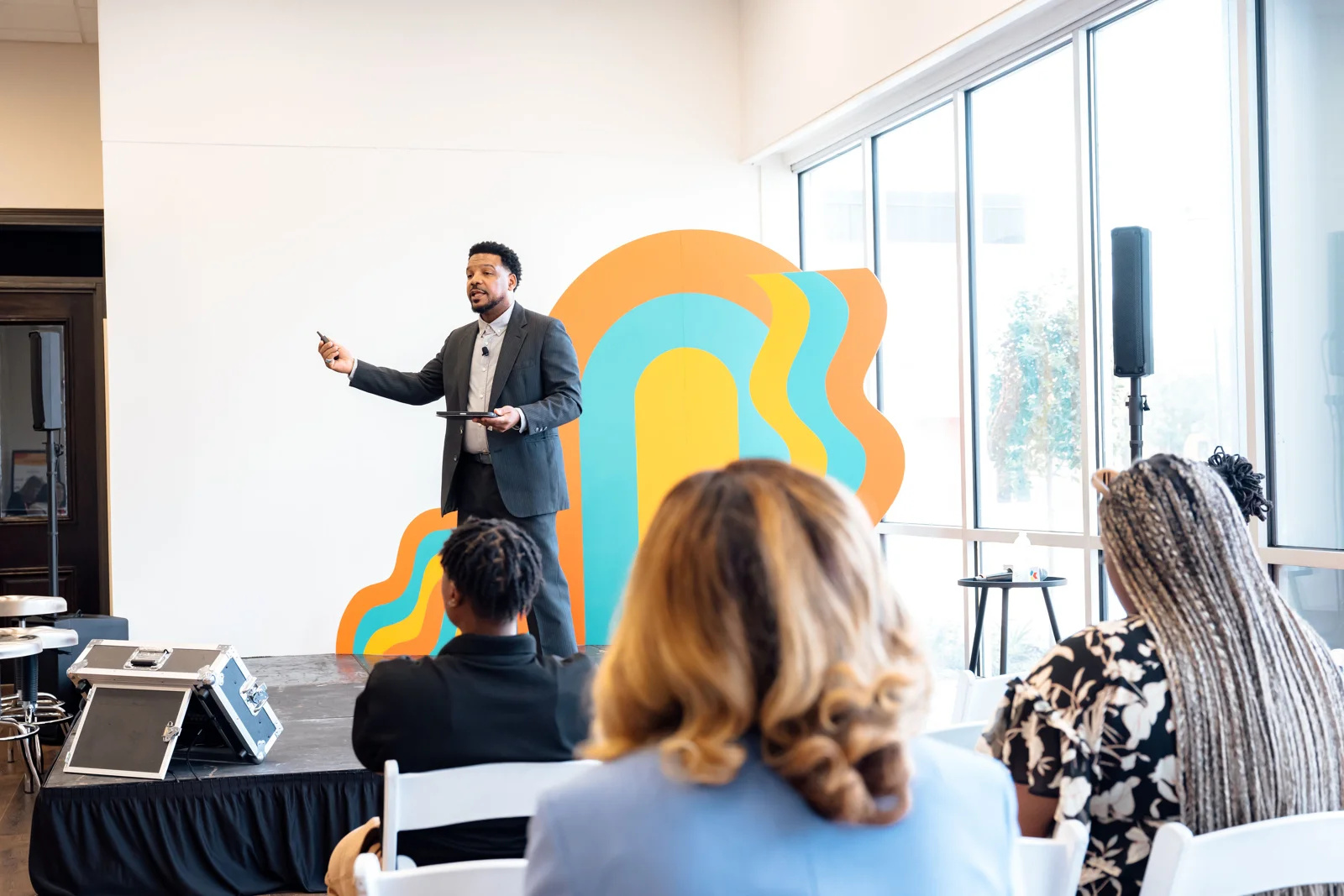 Wiley speaking to an audience seated at tables during a professional learning session